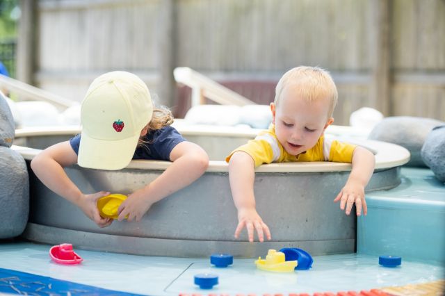 kiddos playing with toy boats in a river simulation at the splash pad
